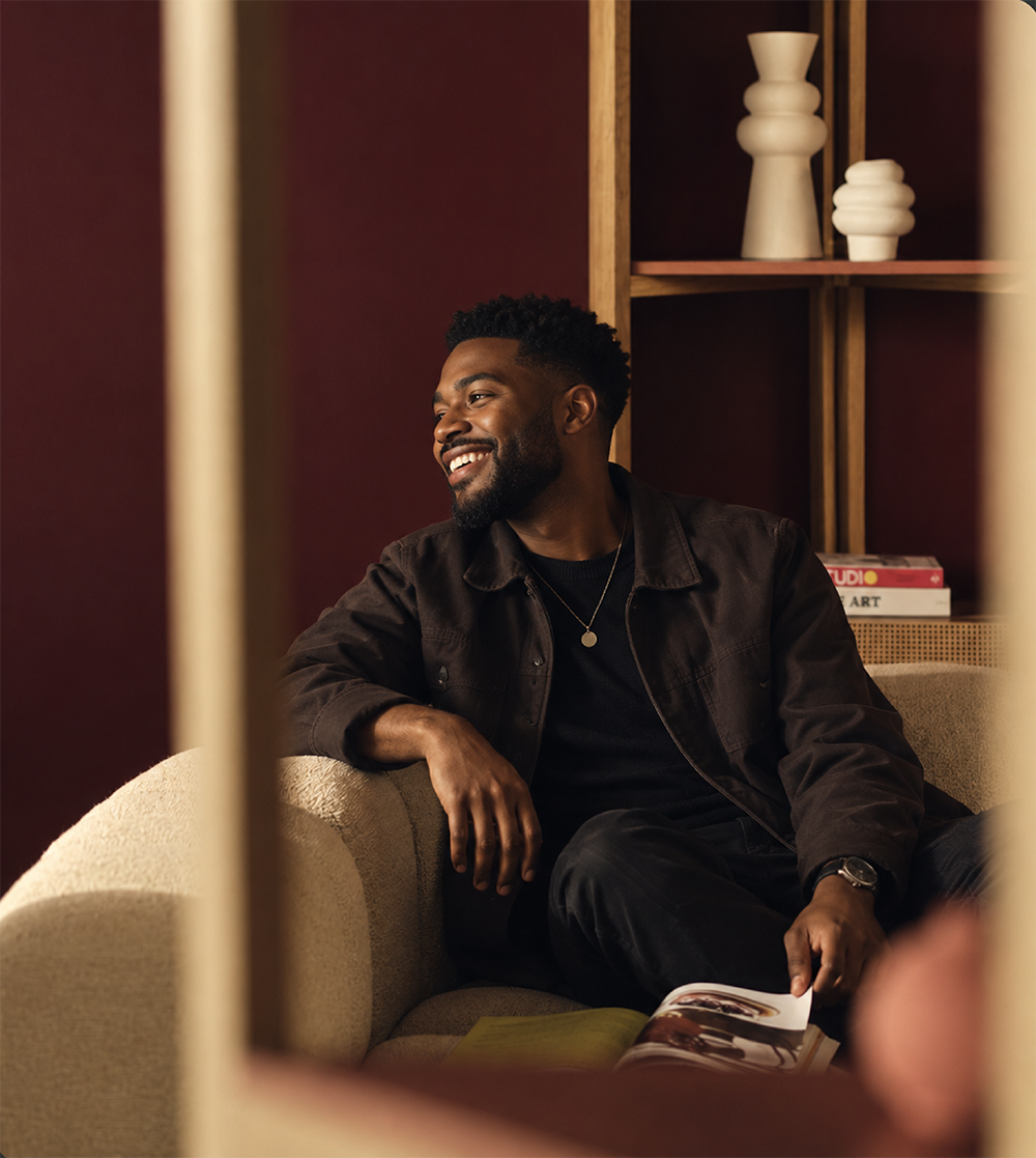 A smiling person seated in a warmly lit room
